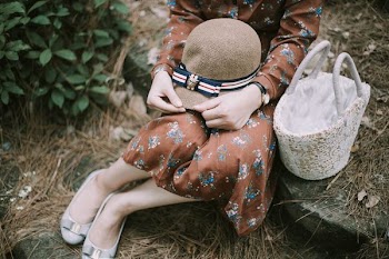 woman sitting on stone with hat on her thigh