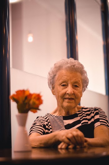 Woman Sitting on Table With Flower and Vase