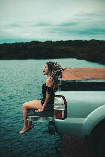 Woman Sitting On Tailgate Of Truck
