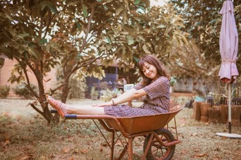 Woman Sitting on Wheelbarrow Under Green Leafed Tree