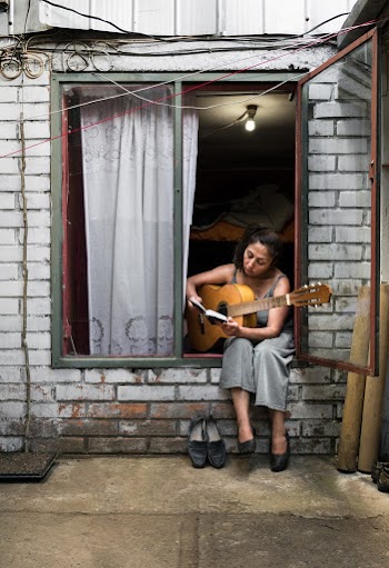 Woman Sitting on Window While Holding Brown Guitar
