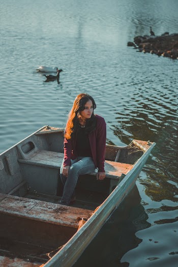 Woman Sitting on Wooden Boat on Body of Water