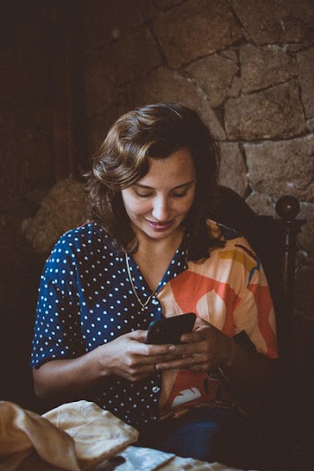 Woman Sitting on Wooden Chair While Using Smartphone