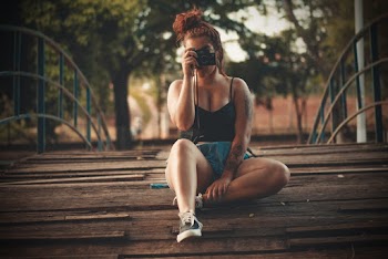 Woman Sitting on Wooden Floor Holding Camera