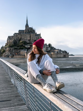 Woman Sitting on Wooden Frame Beside Sea