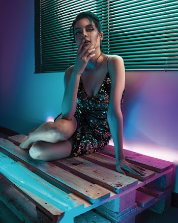 Woman Sitting on Wooden Pallet  With Her  Fingers on Her Chin Beside a Window