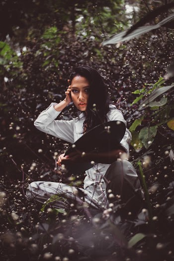 Woman Sitting Surrounded With Green Leaf Plants