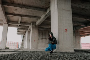 Woman Sitting Under Concrete Bridge