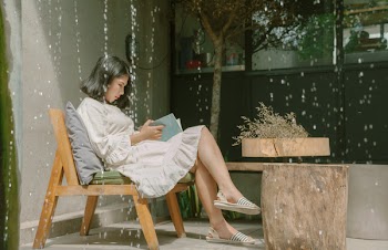 Woman Sitting While Reading a Book