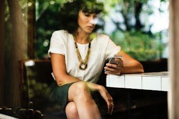 woman sitting while using her smartphone