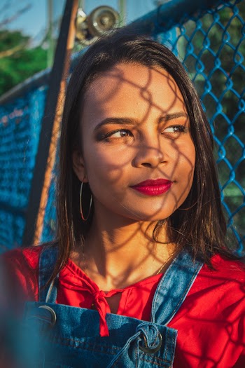 Woman Smiles and Leans Beside Blue Painted Chain-linked Fence