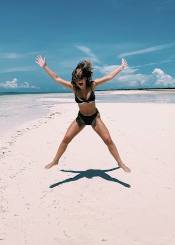 Woman Smiling and Jumping in Mid Air at the Beach during Day