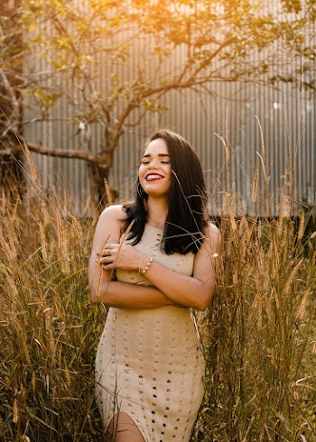 Woman Smiling and Standing on Grass in Front of Tree