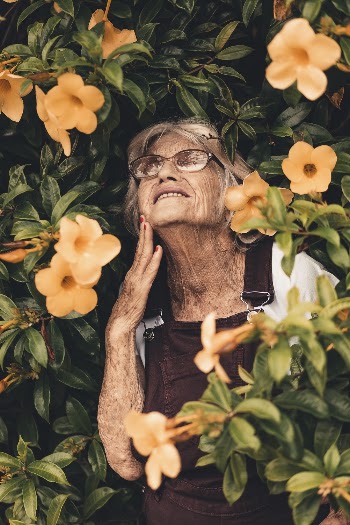 Woman Smiling Standing on Yellow Bell Flower Plant
