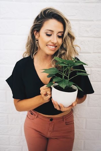 woman smiling while holding potted plant
