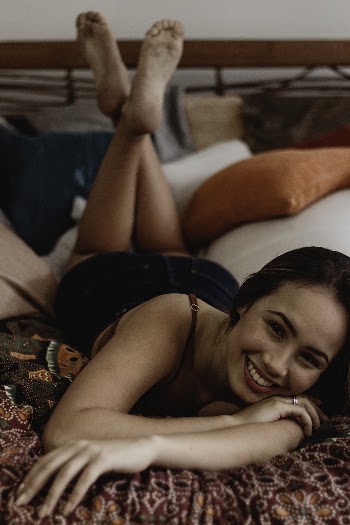 Woman Smiling while Lying Down on Bed