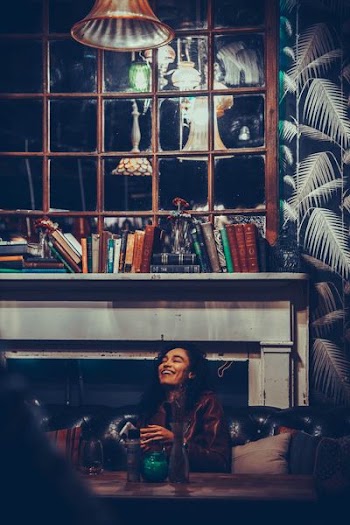 woman smiling while sitting on sofa and holding phone