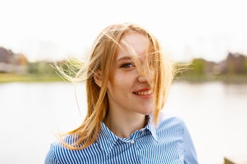 Woman Smiling While Standing Beside Body of Water