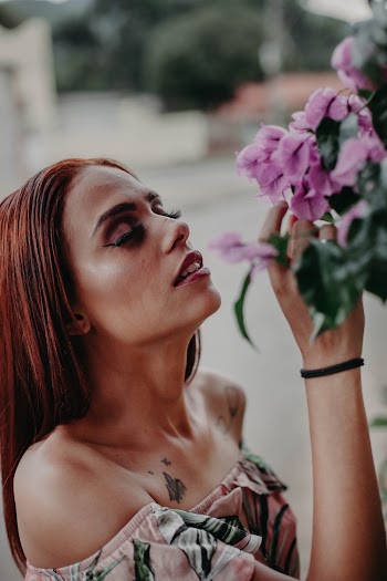 Woman Sniffing a Purple-petaled Flowering Plant