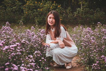 Woman Squatting Beside Purple Flowers