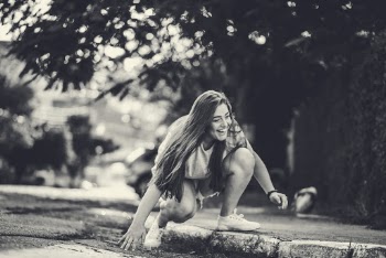 Woman Squatting By The Road Curb