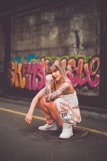 woman squatting in front of graffiti