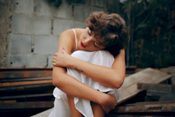 Woman Squatting Near Gray Concrete Wall