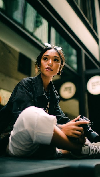 Woman Squatting On The Floor Holding A Dslr Camera
