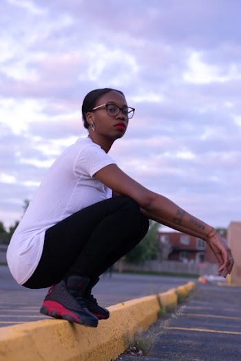 Woman Squatting on Yellow Parking Lot Barrier