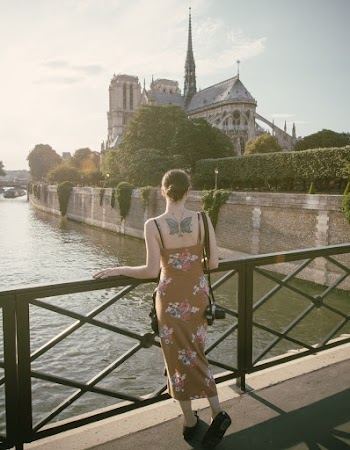 Woman Standing and Holding on Black Railings Near Brown Castle and Body of Water