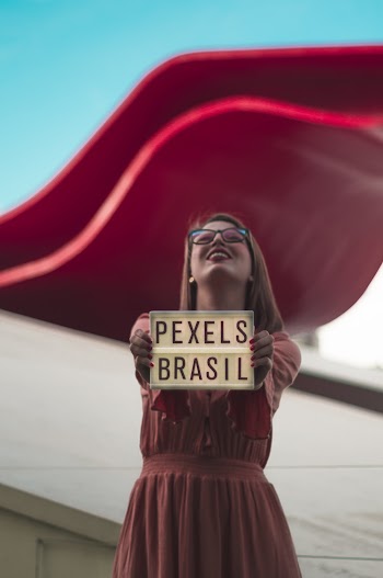 Woman Standing and Holding Pexels Brasil Sign and Smiling