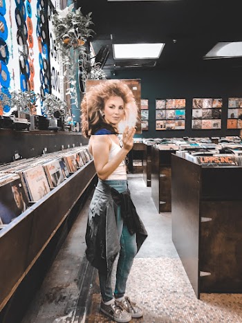 Woman Standing and Holding Vinyl Record Sleeve Inside Shop