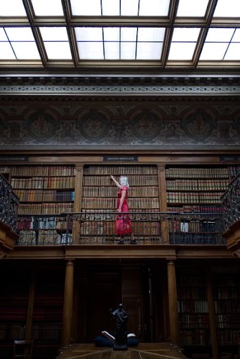 woman standing and picking up book in library