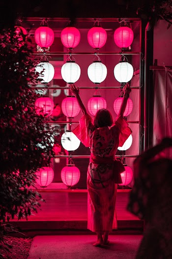 Woman Standing and Raising Both Hands Above Near White-and-pink Lamps