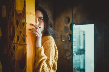 Woman Standing Behind Yellow Wall