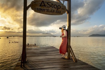 Woman Standing Below the a Stop Vinh Xuan Dai Signage