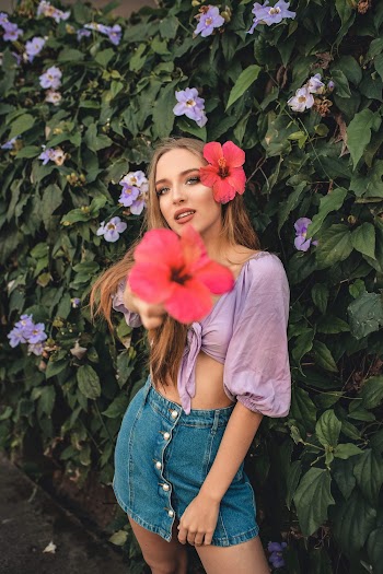 Woman Standing Beside a Flowering Vine With Red Gumamela Flower On Her Hair