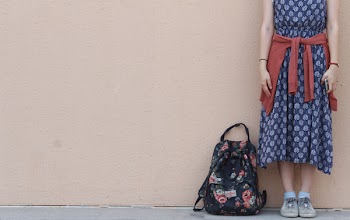 Woman Standing Beside Backpack Near Wall