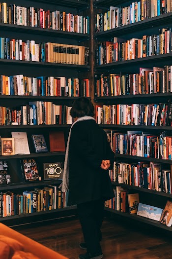Woman Standing Beside Bookcase