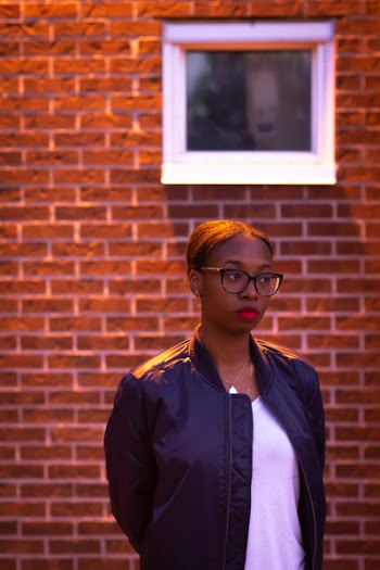 Woman Standing Beside Brown Brick Wall
