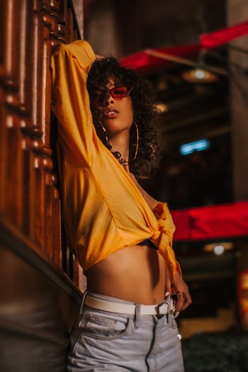 Woman Standing Beside Brown Wooden Surface While Doing Modeling Pose