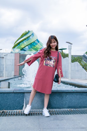 Woman Standing Beside Gray Concrete Outdoor Fountain Under Blue and White Cloudy Skies at Daytime