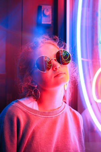 woman standing beside neon signage