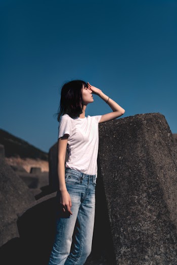 Woman Standing Beside Rock With Hand on Face