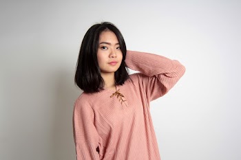 Woman Standing Beside Wall Putting Hands on Neck