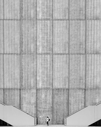 woman standing between two grey concrete stairs beside high-rise building