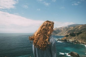 woman standing facing the ocean during daytime