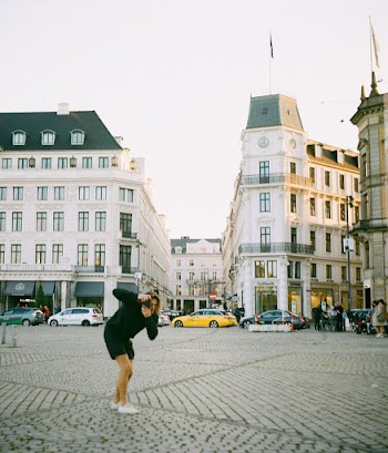 Woman Standing Front of Concrete Buildings Taking A Picture