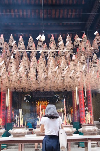 Woman Standing in Front of Incense Burners