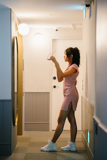 Woman Standing In Front Of Mirror Holding Sunglasses